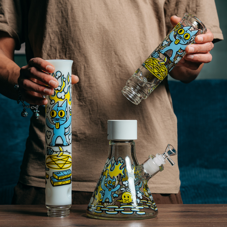 A man disassembling a Classic Size Prism collection single stack bong with a clear beaker base, white halo connector, and interchangeable clear and tall white mouthpieces, all featuring the 666 cat decal family design.