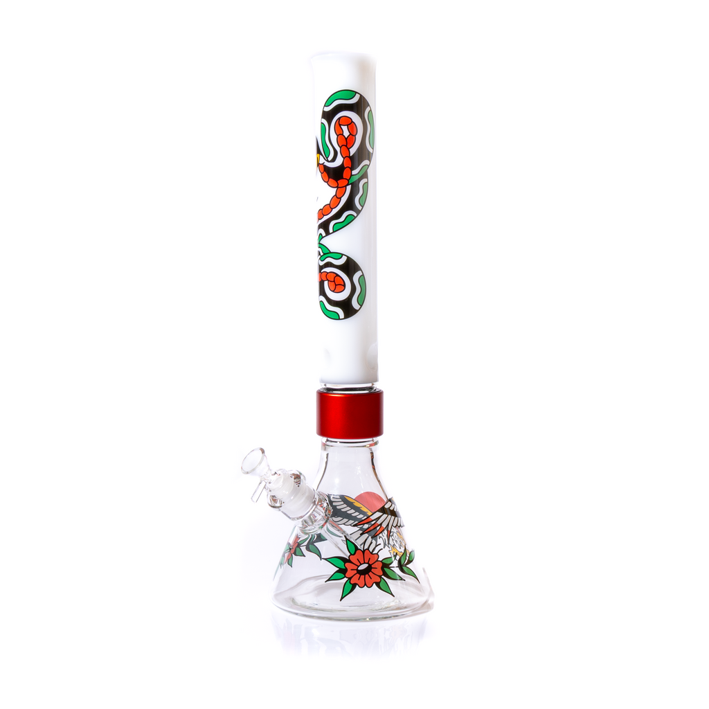 Affordable modular glass bong with American Traditional tattoo decals. The Prism Inked Beaker Single Stack features thick borosilicate glass construction and easy-clean threaded joints. Image shows the assembled piece with a clear beaker base, eagle and flower decal, and a red halo connector. The Tall mouthpiece is white with a snake tattoo decal. Includes clear dry herb bowl and downstem. Customizable water pipe for easy cleaning and budget-friendly setup.