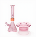 Jane West Ultimate Bundle featuring the pink Prism x Jane West MINI Beaker Bong and matching Twenties Collection Ashtray. The luxury smoking set highlights the diamond-patterned textured glassware and cohesive amber color. The MINI Beaker water pipe is shown with a gold-colored MINI halo connector and 14mm male bowl. Premium glass bundle, designer smoking set, collaborative cannabis glassware, matching amber bong and ashtray, Twenties Collection water pipe.