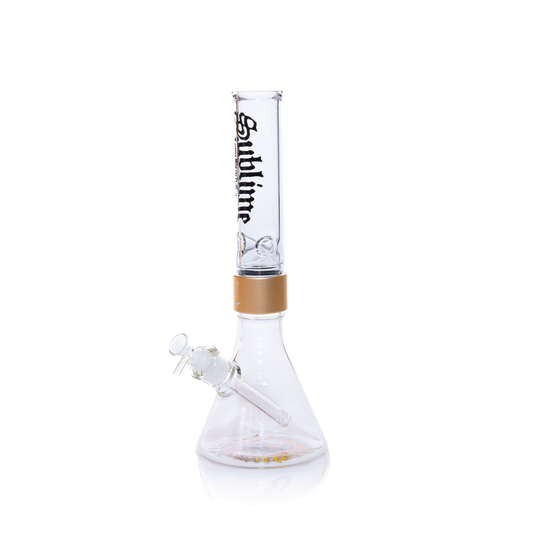 A fully assembled Prism x Sublime official clear glass modular beaker bong. The transparent design offers a clean look, showcasing the gold Halo Connector and the iconic yellow sun logo on the base. The clear glass mouthpiece features the black Sublime gothic logo, emphasizing the "Long Beach, California" roots of the band.