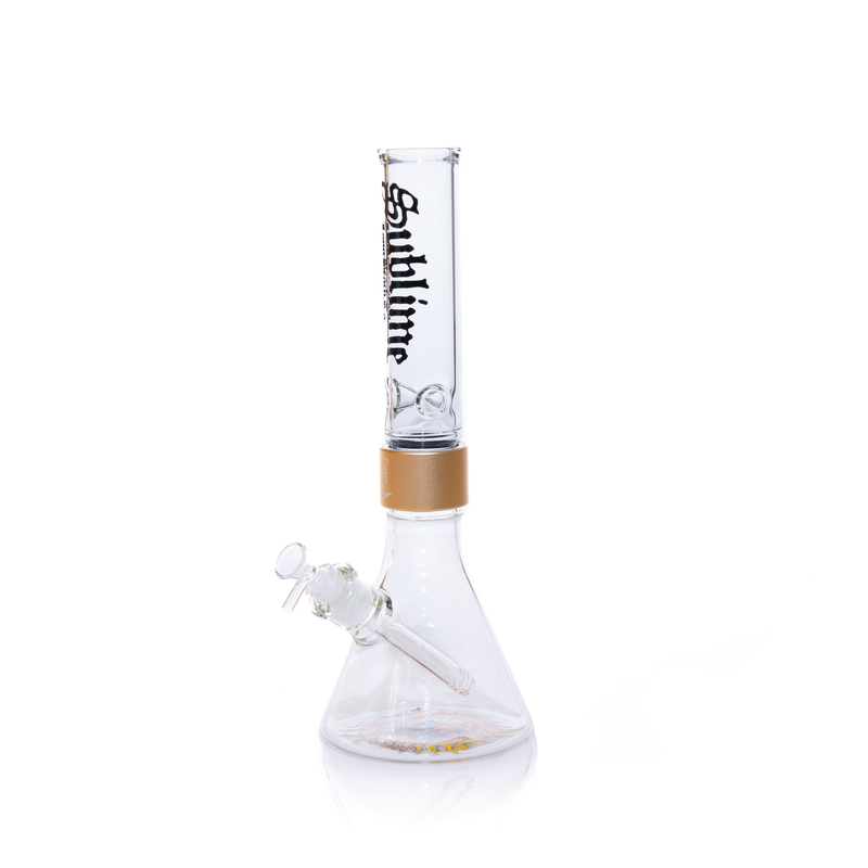 A fully assembled Prism x Sublime official clear glass modular beaker bong. The transparent design offers a clean look, showcasing the gold Halo Connector and the iconic yellow sun logo on the base. The clear glass mouthpiece features the black Sublime gothic logo, emphasizing the "Long Beach, California" roots of the band.