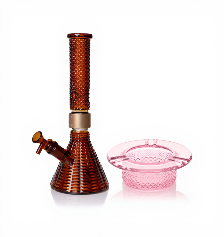 Jane West Ultimate Bundle featuring the amber Prism x Jane West MINI Beaker Bong and matching Twenties Collection Ashtray. The luxury smoking set highlights the diamond-patterned textured glassware and cohesive amber color. The MINI Beaker water pipe is shown with a gold-colored MINI halo connector and 14mm male bowl. Premium glass bundle, designer smoking set, collaborative cannabis glassware, matching amber bong and ashtray, Twenties Collection water pipe.