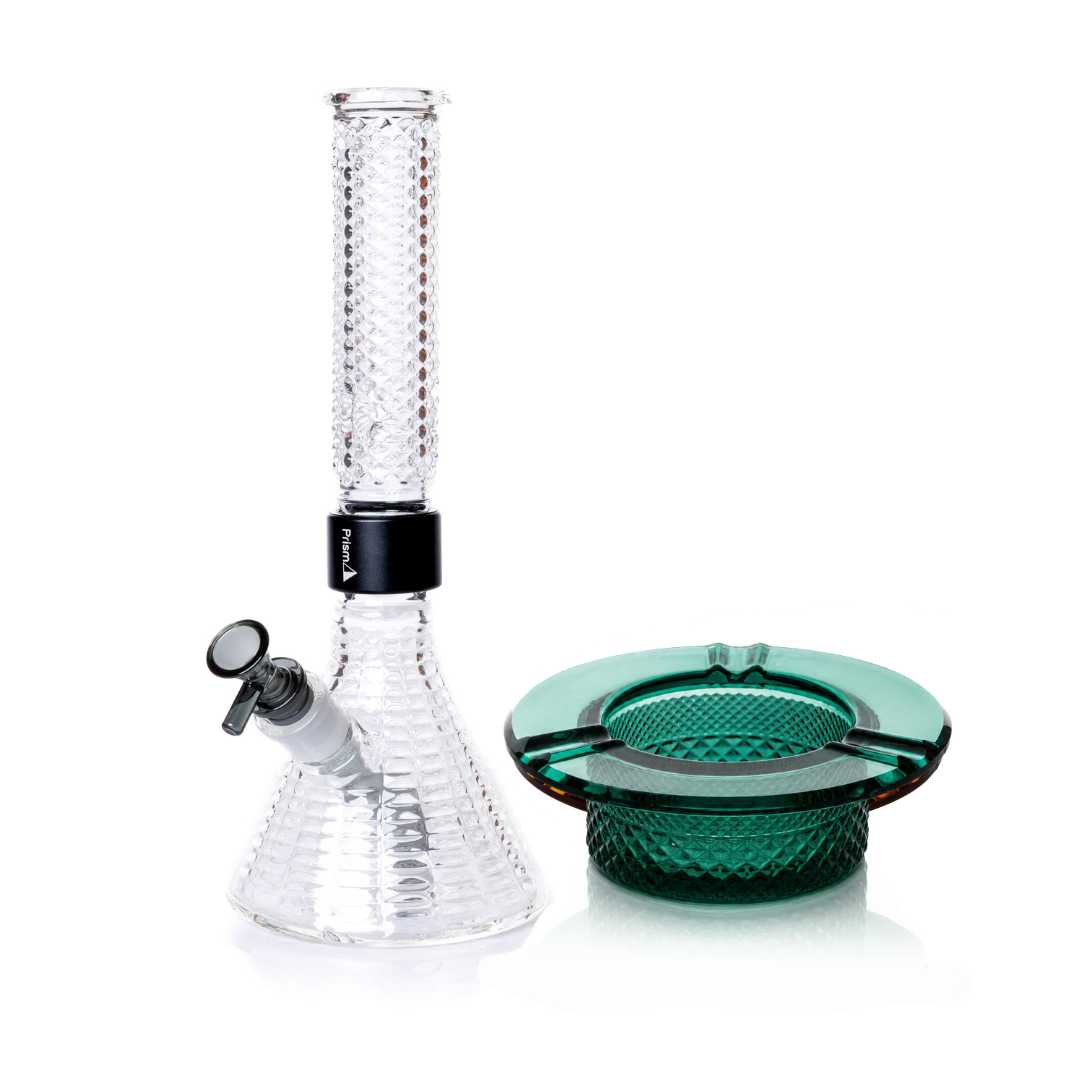 Jane West Ultimate Bundle featuring the clear Prism x Jane West MINI Beaker Bong and matching Twenties Collection Ashtray. The luxury smoking set highlights the diamond-patterned textured glassware and cohesive amber color. The MINI Beaker water pipe is shown with a gold-colored MINI halo connector and 14mm male bowl. Premium glass bundle, designer smoking set, collaborative cannabis glassware, matching amber bong and ashtray, Twenties Collection water pipe.