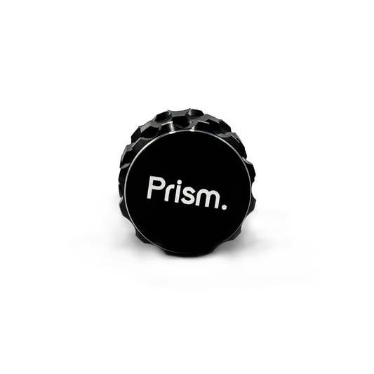 Black 3-Piece aluminum cannabis grinder by Prism Water Pipes. Side view shows branded faceplate and silver, ergonomic grip accents.
