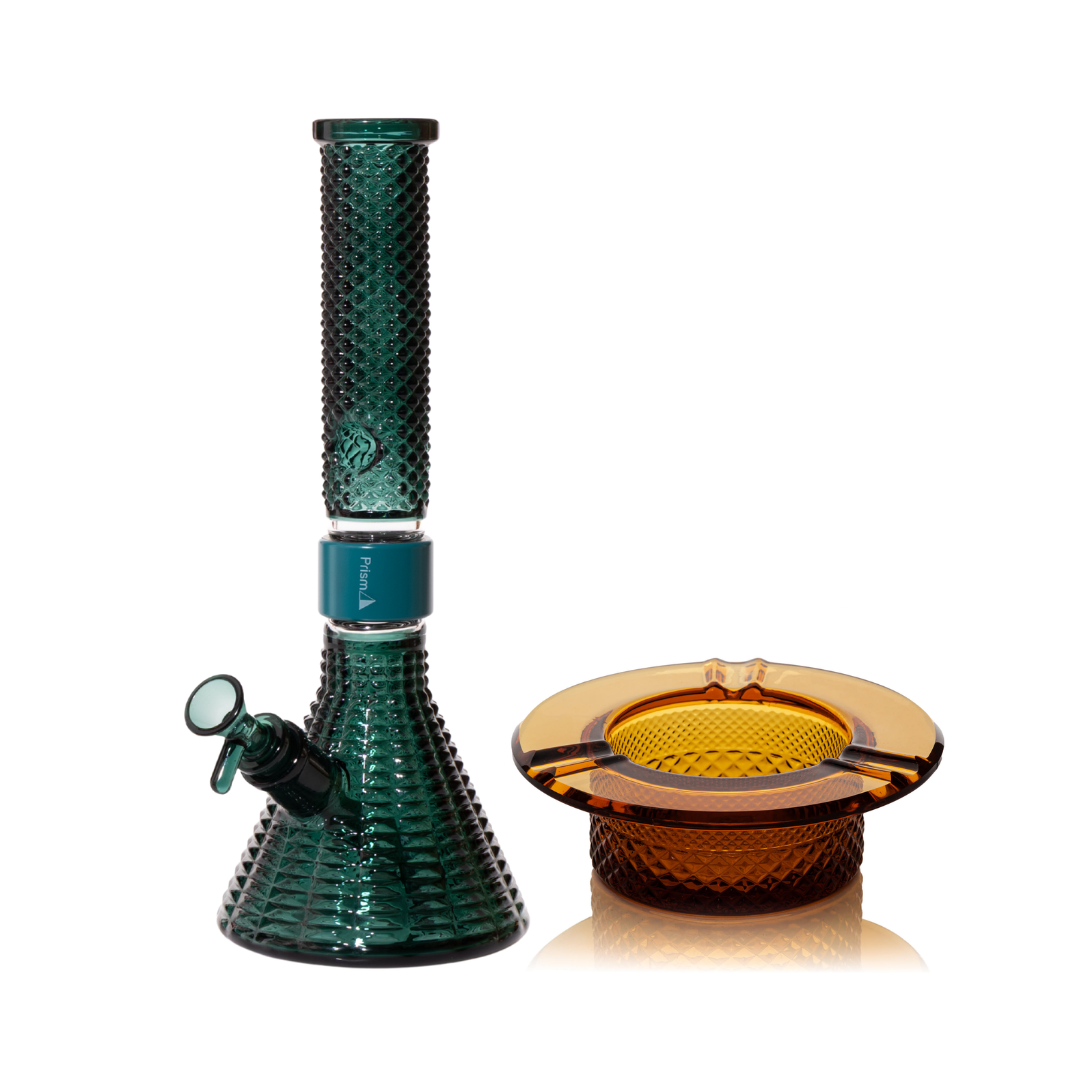 Jane West Ultimate Bundle featuring the teal Prism x Jane West MINI Beaker Bong and matching Twenties Collection Ashtray. The luxury smoking set highlights the diamond-patterned textured glassware and cohesive teal color. The MINI Beaker water pipe is shown with a teal-colored MINI halo connector and 14mm male bowl. Premium glass bundle, designer smoking set, collaborative cannabis glassware, matching amber bong and ashtray, Twenties Collection water pipe.