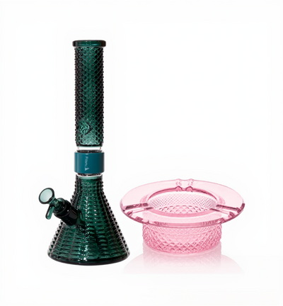 Jane West Ultimate Bundle featuring the teal Prism x Jane West MINI Beaker Bong and matching Twenties Collection Ashtray. The luxury smoking set highlights the diamond-patterned textured glassware and cohesive teal color. The MINI Beaker water pipe is shown with a aqua-colored MINI halo connector and 14mm male bowl. Premium glass bundle, designer smoking set, collaborative cannabis glassware, matching amber bong and ashtray, Twenties Collection water pipe.